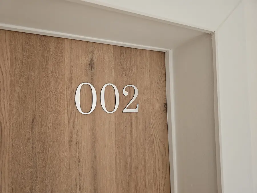 Numéro de chambre 002 posé sur une porte en bois